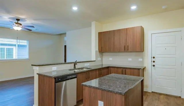 a kitchen with granite countertop wood cabinets a sink and dishwasher