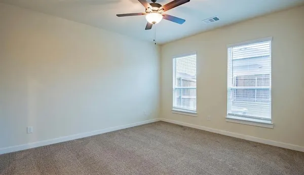 an empty room with windows and fan
