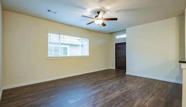 a view of an empty room with wooden floor and a window