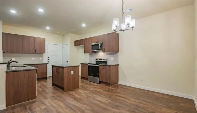 a kitchen with stainless steel appliances granite countertop a stove a sink dishwasher a refrigerator and a oven with wooden floor