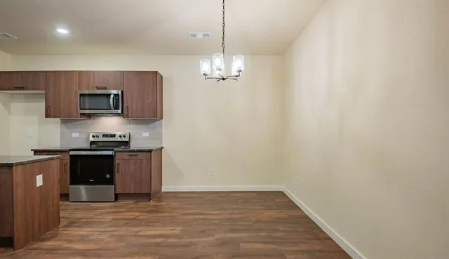 a kitchen with stainless steel appliances granite countertop a refrigerator a stove top oven a sink and dishwasher