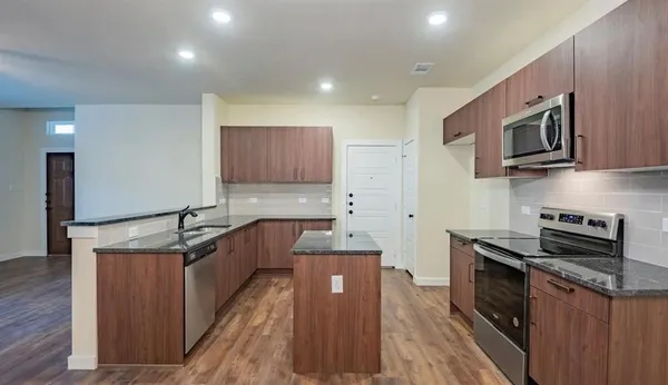 a kitchen with stainless steel appliances granite countertop a stove a sink and a microwave