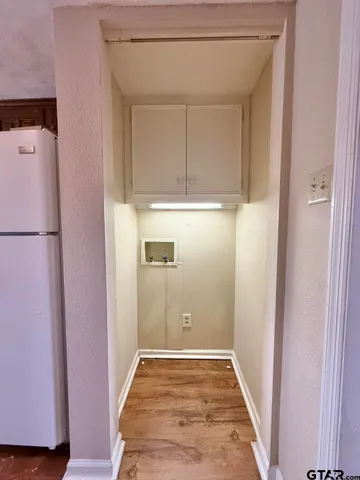 a view of a hallway with wooden floor and cabinet