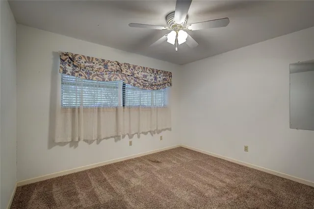 a view of empty room with window and chandelier fan