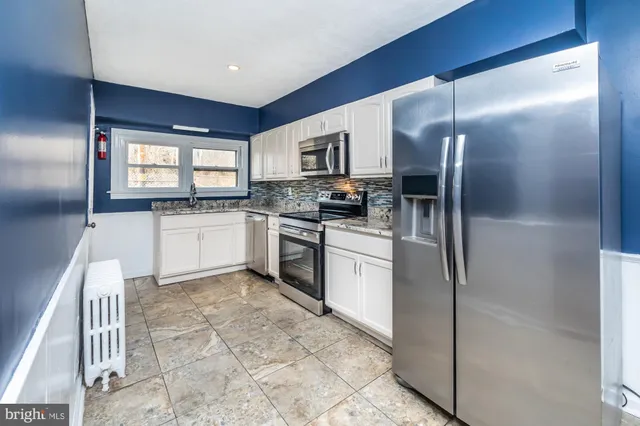a kitchen with granite countertop a refrigerator stove top oven and sink