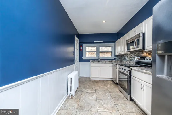a large kitchen with granite countertop a stove a sink and a microwave