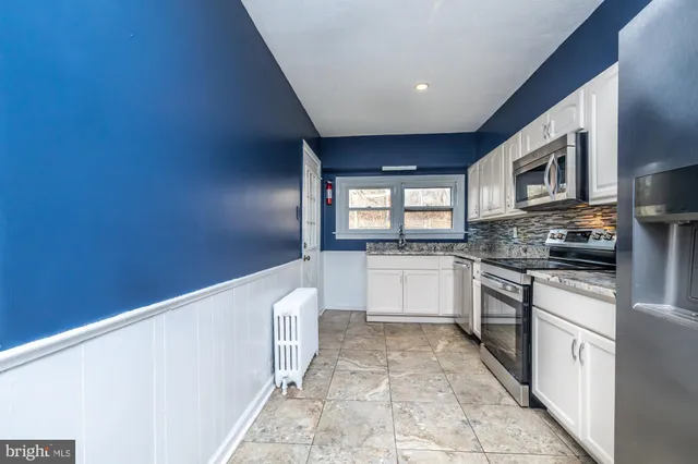 a large kitchen with granite countertop a stove a sink and a microwave