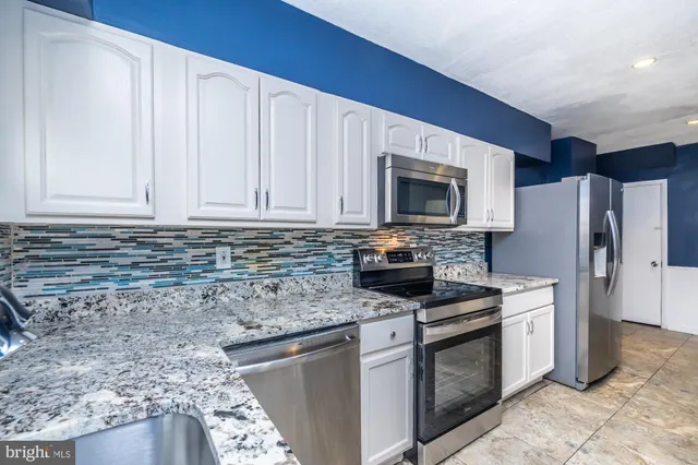 a kitchen with stainless steel appliances granite countertop a refrigerator stove microwave and sink