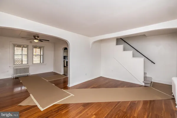 a view of an empty room with wooden floor and stairs