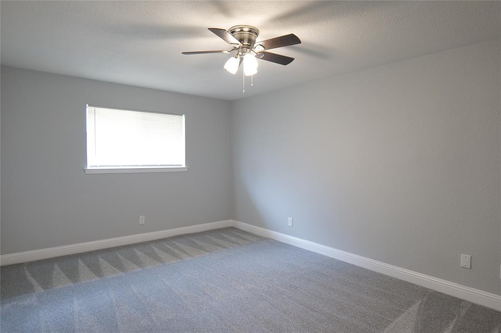 7137 Hunnicut Road Dallas, TX 75227 - Photo 14 of 16 Neutral wall paint, ceiling fan with integrated lighting, window with blinds, and carpeting