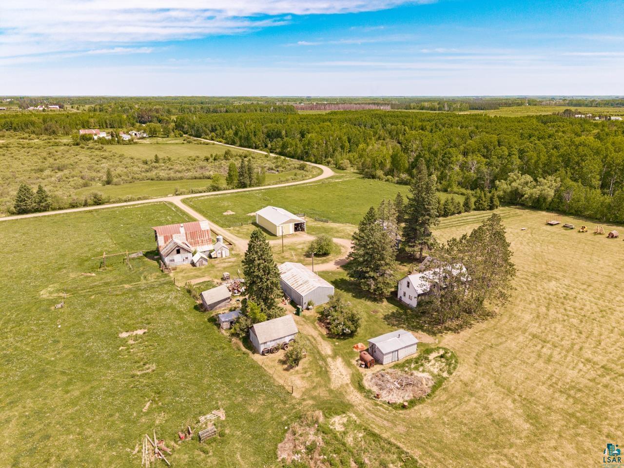 6606 Metso Road Kettle River, MN 55757 - Photo 53 of 84 Expansive agricultural property featuring multiple outbuildings, mature evergreen trees, and surrounding open fields