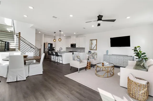 a living room with furniture kitchen view and a wooden floor