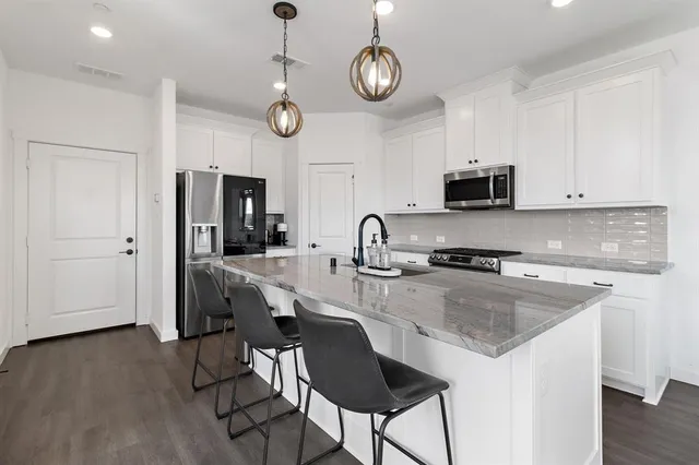 a kitchen with stainless steel appliances granite countertop a stove top oven a refrigerator a sink and dishwasher with wooden floor