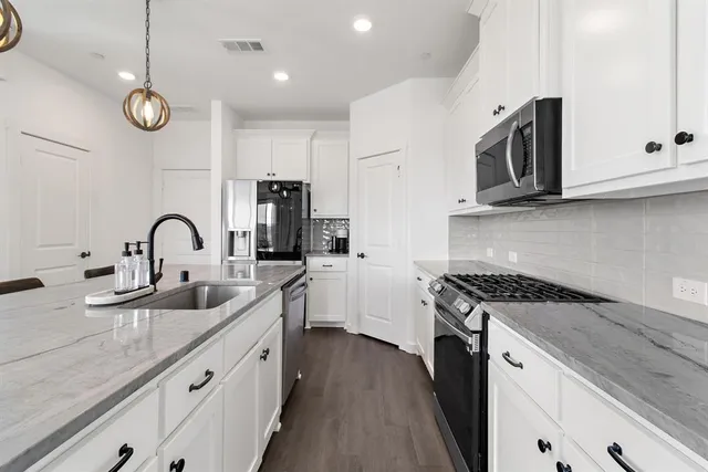 a kitchen with stainless steel appliances granite countertop a sink a stove and cabinets
