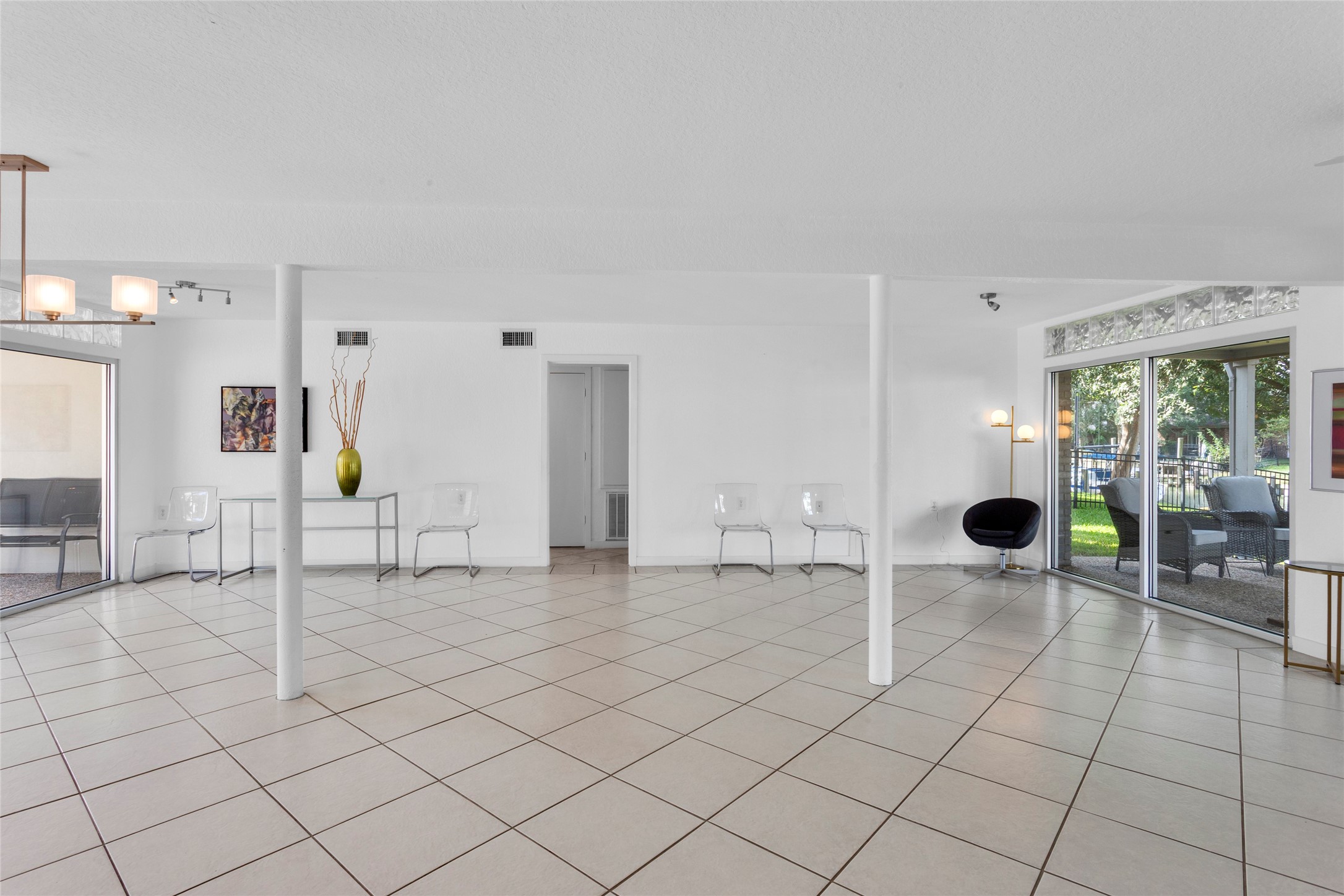 67 Harbor Lane Kemah, TX 77565 - Photo 28 of 47 This spacious room features large floor tiles and ample natural light from sliding glass doors, leading to a patio with outdoor seating. The minimalist decor includes modern chairs and a sleek console table, creating a clean and open atmosphere.