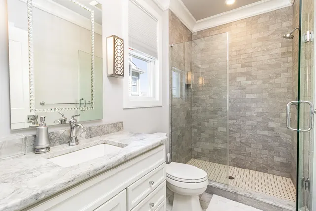 a bathroom with a granite countertop sink a toilet a mirror and shower