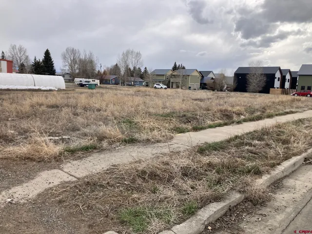 a view of a dry yard with wooden fence