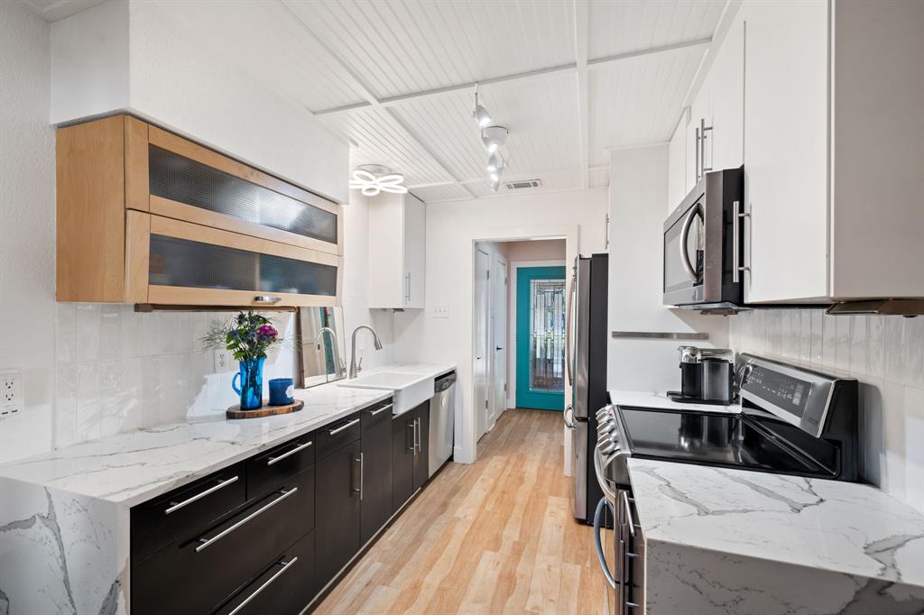 7496 East Northwest Highway, Unit 145 Dallas, TX 75231 - Photo 4 of 35 a kitchen with stainless steel appliances a sink dishwasher a stove top oven a refrigerator with wooden floor