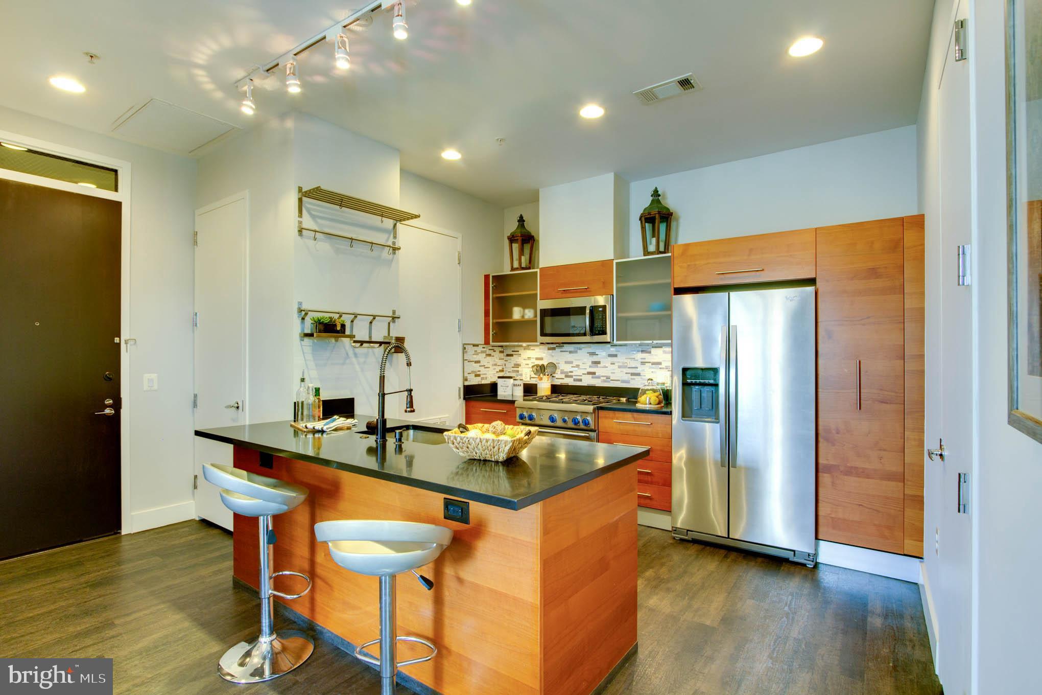 a kitchen with stainless steel appliances granite countertop a refrigerator a stove top oven and a refrigerator