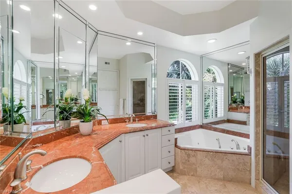a bathroom with a granite countertop tub sink and mirror