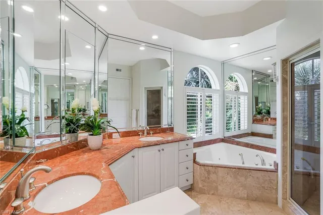 a bathroom with a granite countertop tub sink and mirror