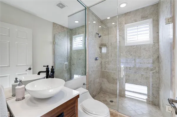 a bathroom with a sink a toilet a glass door and shower