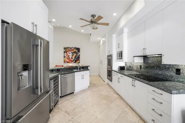 a large kitchen with stainless steel appliances granite countertop a refrigerator and a sink