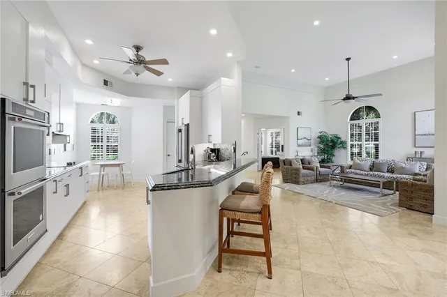a large white kitchen with lots of counter space a sink a window and stainless steel appliances