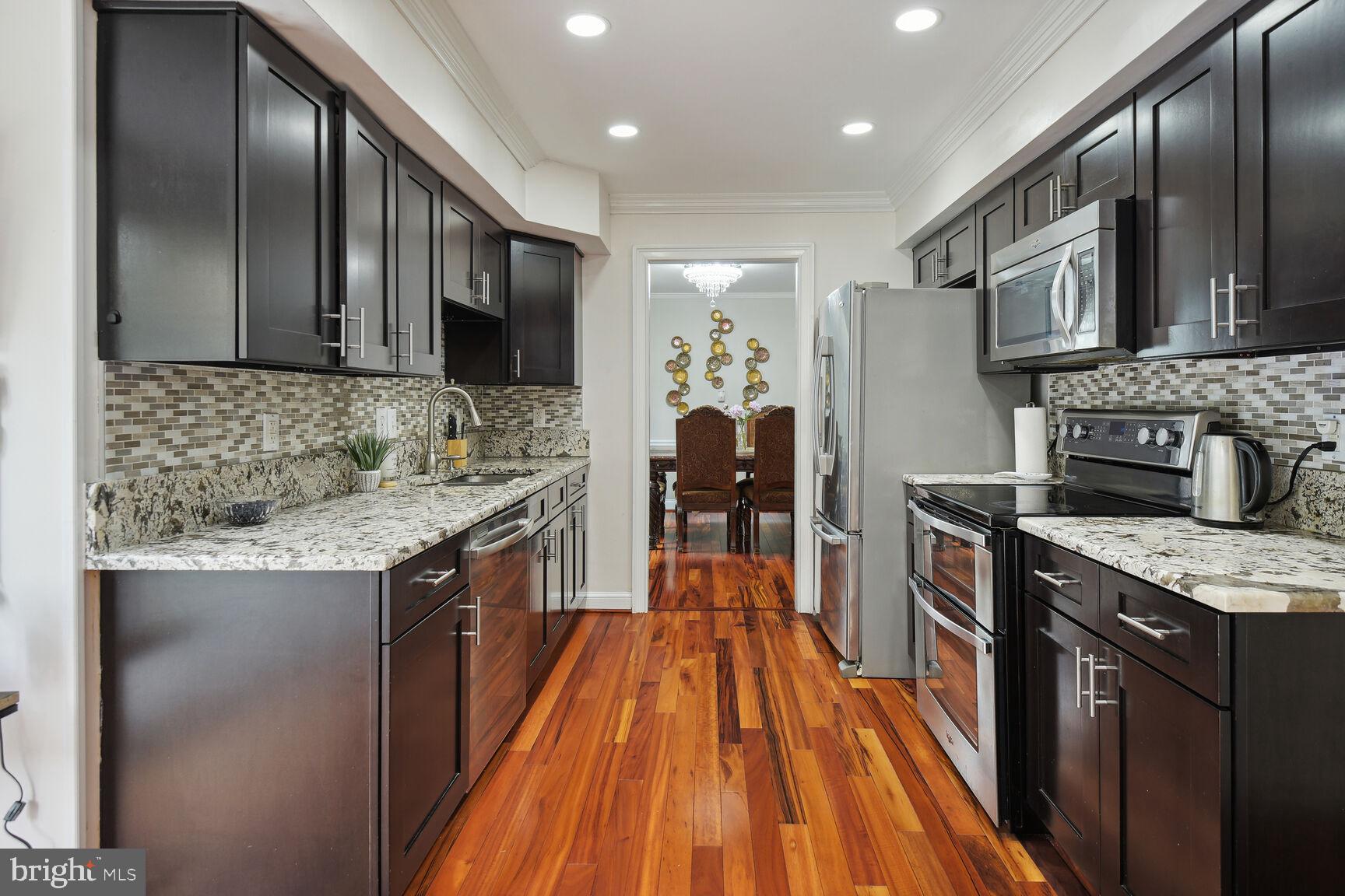 12324 Triple Crown Road North Potomac, MD 20878 - Photo 21 of 49 a kitchen with stainless steel appliances granite countertop a stove top oven a sink dishwasher a refrigerator and a oven with wooden floor