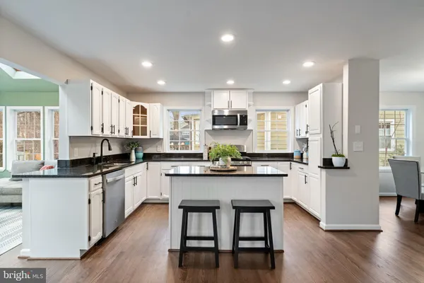 a kitchen with stainless steel appliances a sink a stove a refrigerator cabinets and wooden floor