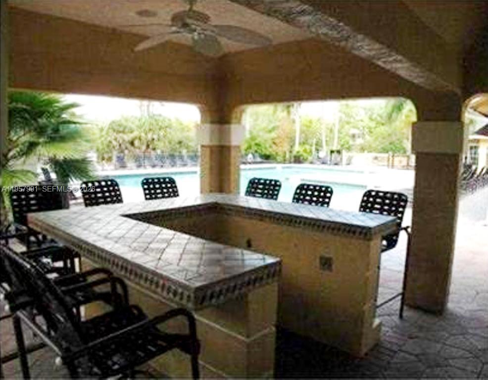 4055 West McNab Road, Unit H311 Pompano Beach, FL 33069 - Photo 13 of 14 a view of a patio with table and chairs under an umbrella with a large tree