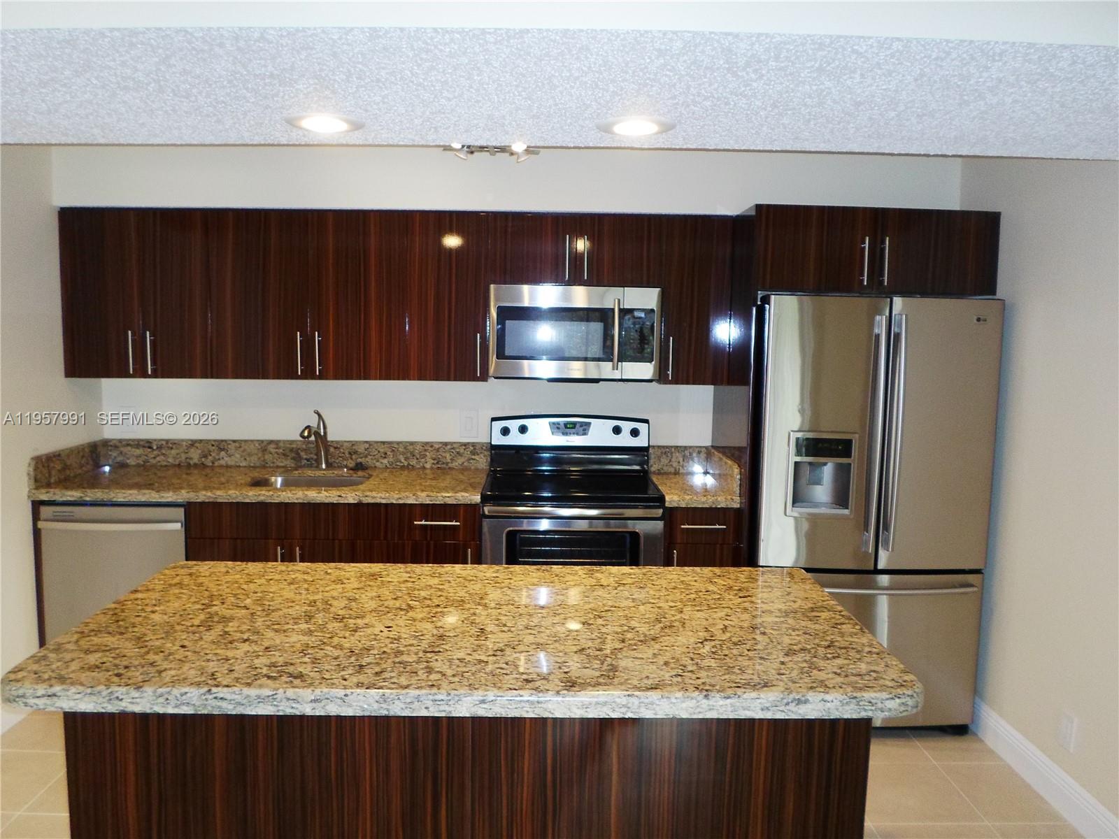 4055 West McNab Road, Unit H311 Pompano Beach, FL 33069 - Photo 2 of 14 a kitchen with stainless steel appliances granite countertop a stove a refrigerator and a sink
