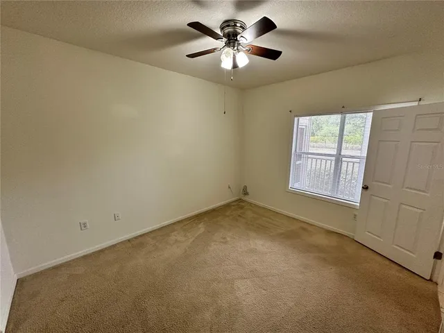 an empty room with windows and fan