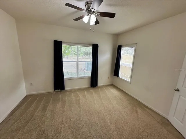 a view of an empty room with window chandelier fan