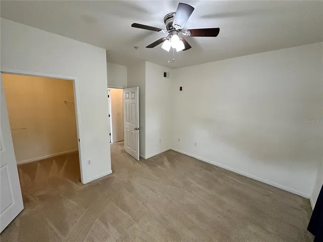 an empty room with a chandelier fan and windows