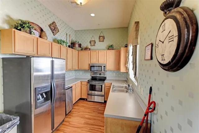 a kitchen with stainless steel appliances granite countertop a refrigerator a stove and a sink with wooden floor
