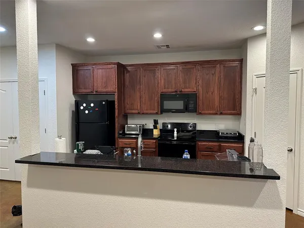 a kitchen with kitchen island granite countertop a stove top oven a sink a counter space and cabinets