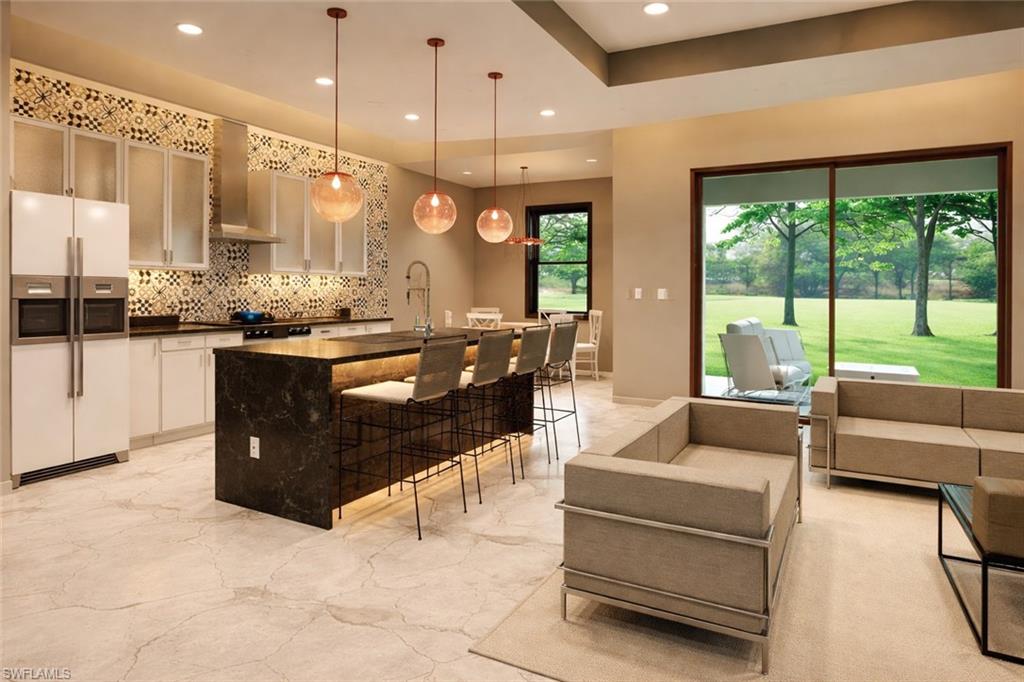 100 Parish Drive Lehigh Acres, FL 33974 - Photo 2 of 3 Kitchen with an island with sink, white refrigerator with ice dispenser, a kitchen breakfast bar, decorative light fixtures, and decorative backsplash