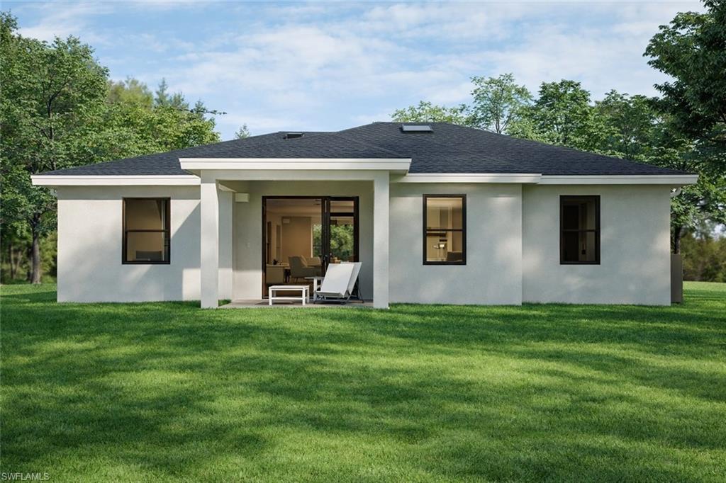 100 Parish Drive Lehigh Acres, FL 33974 - Photo 3 of 3 Rear view of property featuring a yard, a patio area, roof with shingles, and stucco siding