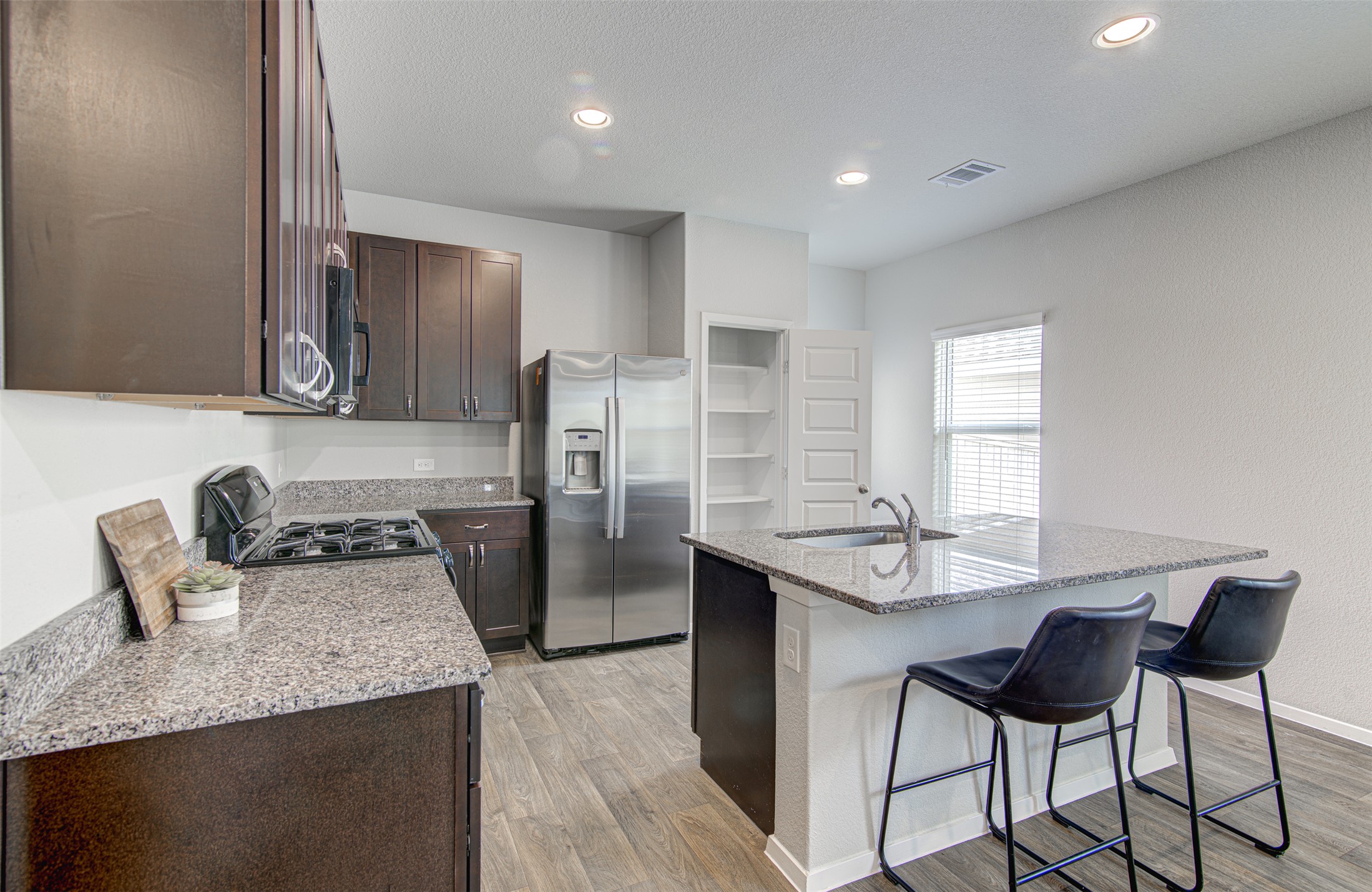 156 Tillage Road Elgin, TX 78621 - Photo 10 of 25 Modern kitchen with granite countertops and stainless steel appliances awaits culinary adventures.