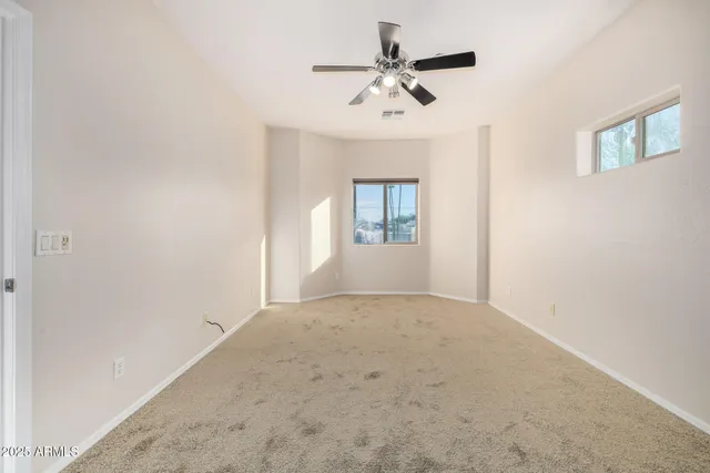 an empty room with windows and fan