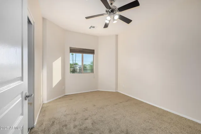 an empty room with windows and fan