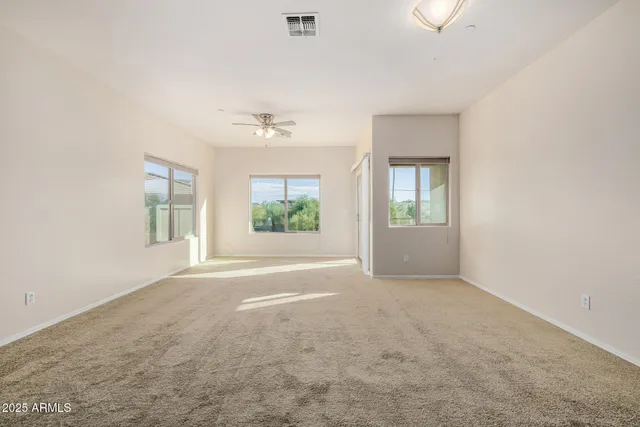 an empty room with windows and chandelier fan