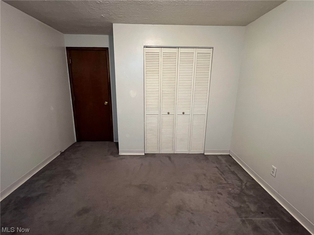 36555 Flat Rock Road Barnesville, OH 43713 - Photo 21 of 35 Unfurnished bedroom featuring a textured ceiling, dark colored carpet, and a closet