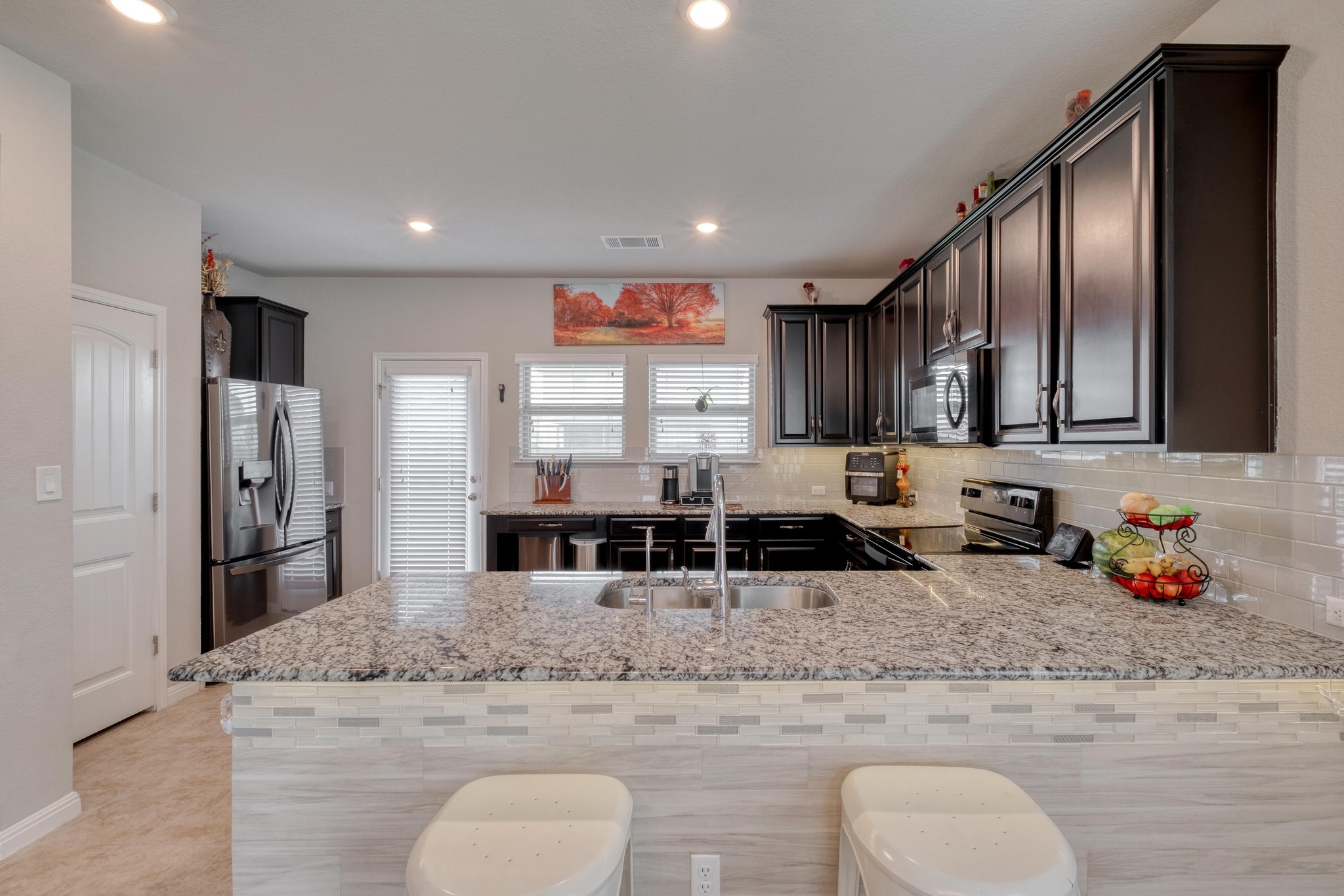 19028 Quebrada Drive Pflugerville, TX 78660 - Photo 13 of 36 a kitchen with stainless steel appliances granite countertop a sink a stove and a refrigerator