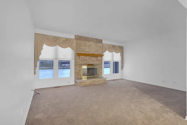 an empty room with a fireplace and windows