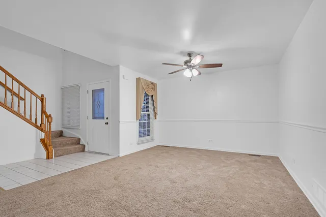 a view of an empty room with a chandelier fan