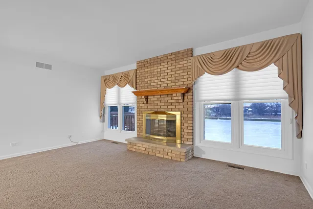 an empty room with a fireplace and large window