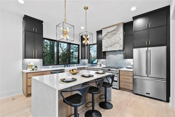 a kitchen with stainless steel appliances a stove a sink a kitchen island and chairs