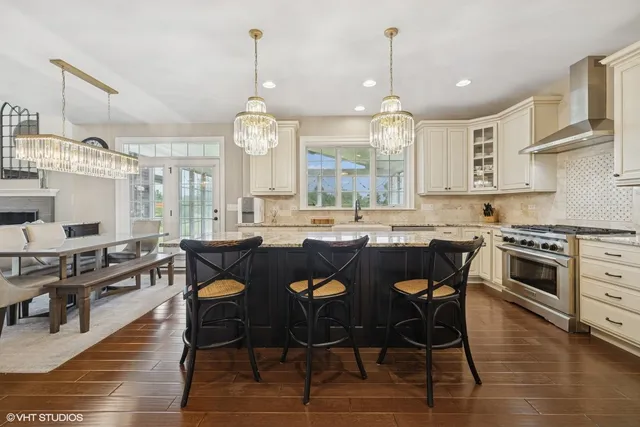 a kitchen with stainless steel appliances granite countertop a stove oven a sink dishwasher and white cabinets with wooden floor